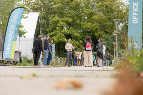 Mensen op WaterStraat op The Green Village luisteren naar man